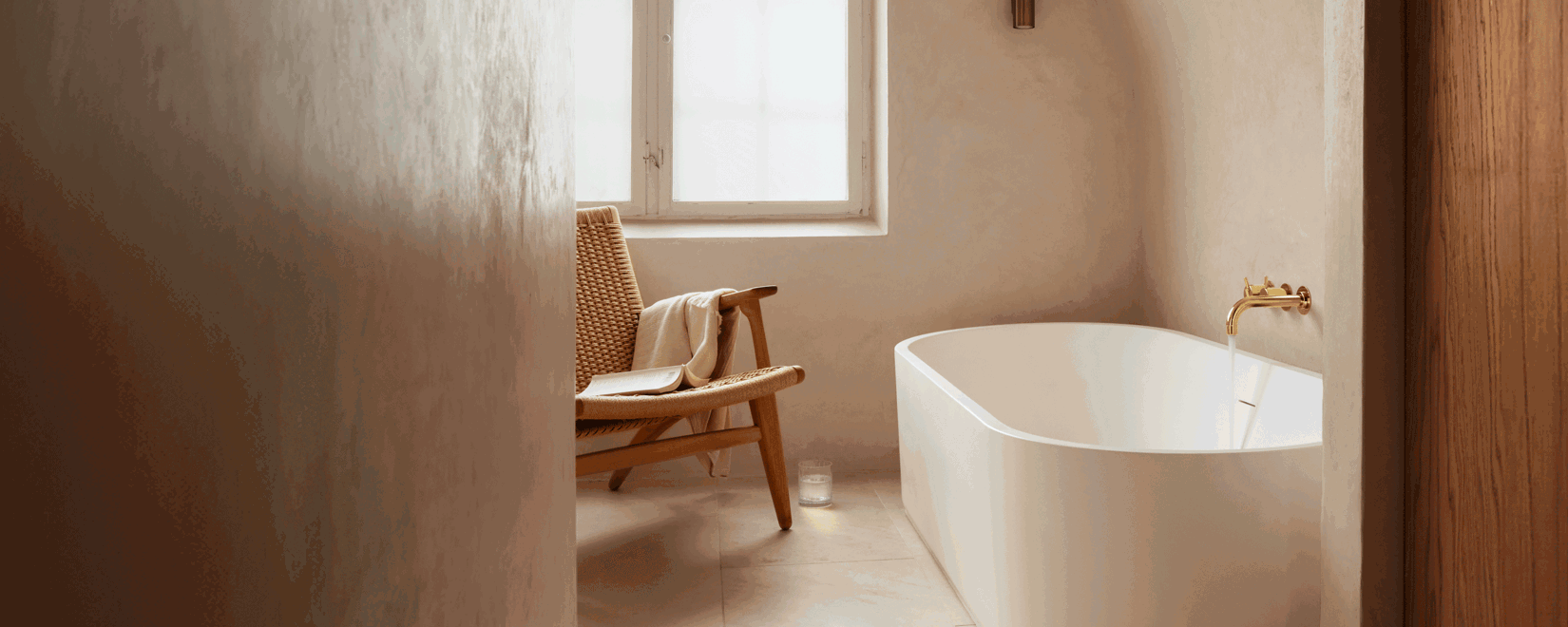 Badewanne mit Armaturen von VOLA in Beige mit goldenem Wasserhahn