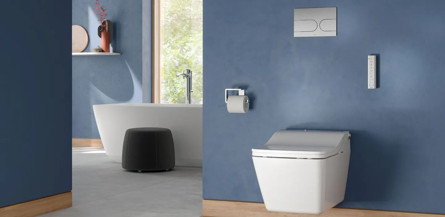 Großes Badezimmer mit blauen Wänden, einem wandhängenden TOTO-SW-WC und einer freistehenden Badewanne im Hintergrund.