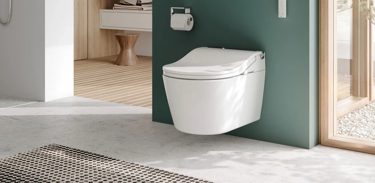 Ein modernes Badezimmer mit einem wandhängenden TOTO-Washlet, das vor einer grünen Wand montiert ist. 