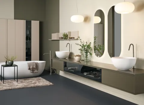 Offenes Badkonzept von Stocco mit Doppelwaschtisch, ovalen Spiegeln, freistehender Wanne und grünen Akzenten.