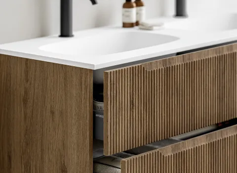 Detailansicht eines Waschtischs mit geriffelter Eichenfront und weißer Waschtischplatte.