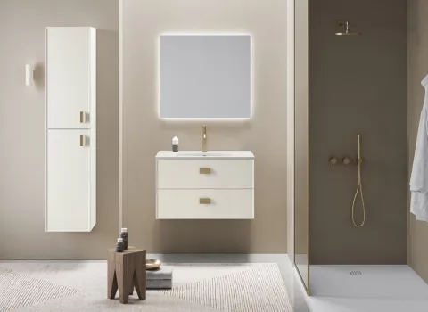 Modernes Badmöbel-Set in Creme mit goldfarbenen Griffen, beleuchtetem Spiegel und integrierter Dusche.