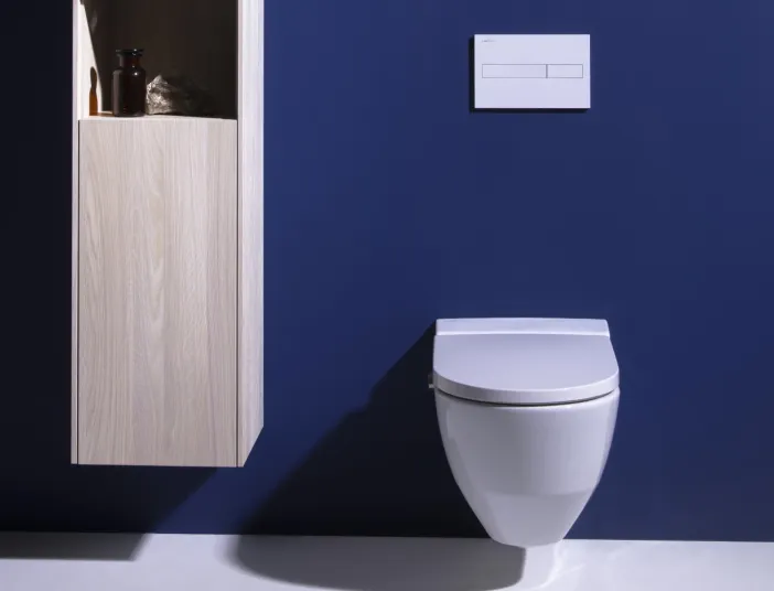 Ein modernes Badezimmer mit einer schwebenden weißen Toilette vor einer dunkelblauen Wand.