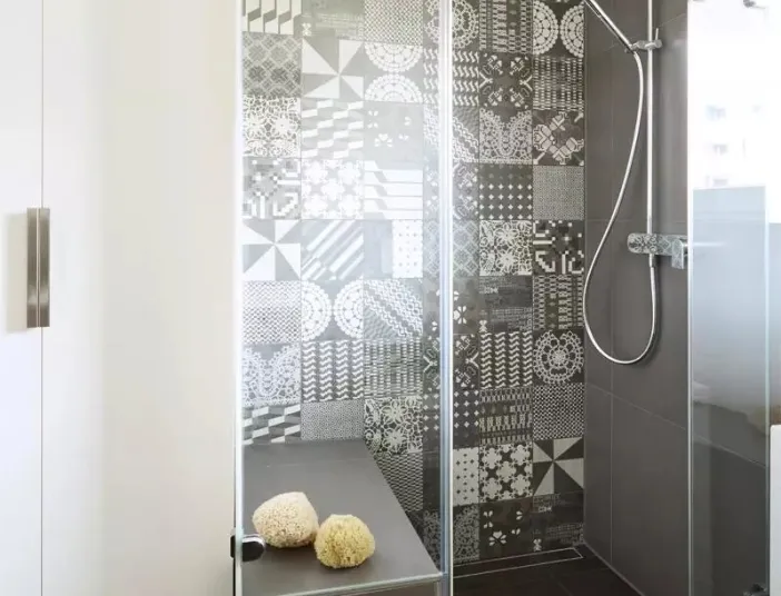 Dusche mit Mosaik und hohem Schrank daneben